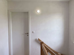 Runde LED-Bullaugenleuchte mit Radarmelder, eingeschaltet an der Wand eines Treppenabsatzes, neutralweißes Licht