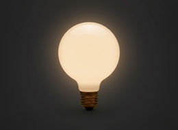 Ampoule globe G95 en verre opalin allumée, lumière douce et diffuse, sur fond gris foncé