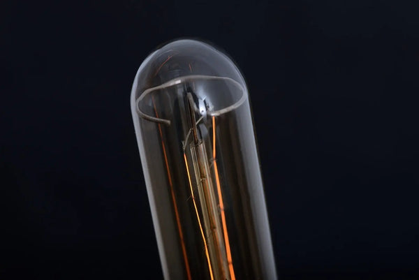 Gros plan sur le sommet arrondi de l'ampoule tube Ron et ses filaments, sur fond noir