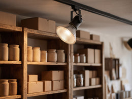 Halogen-Reflektorlampe PAR38 E27 in einem schwarzen Schienenstrahler, der die Holzregale eines Ladens beleuchtet – Anwendungsbeispiel