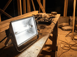 Projecteur de chantier à tube halogène R7s allumé, posé sur un établi en bois dans un bâtiment en travaux