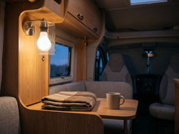 Ampoule LED basse tension allumée dans une applique, au-dessus de la table d'un camping-car, en lumière chaude