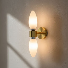 Applique murale double en laiton avec deux ampoules flamme dépolies allumées, sur un mur crépi